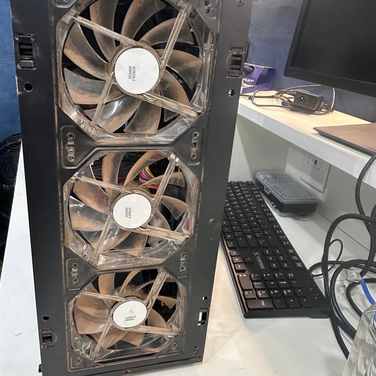 Painel frontal de gabinete removido, com três coolers cobertos de poeira